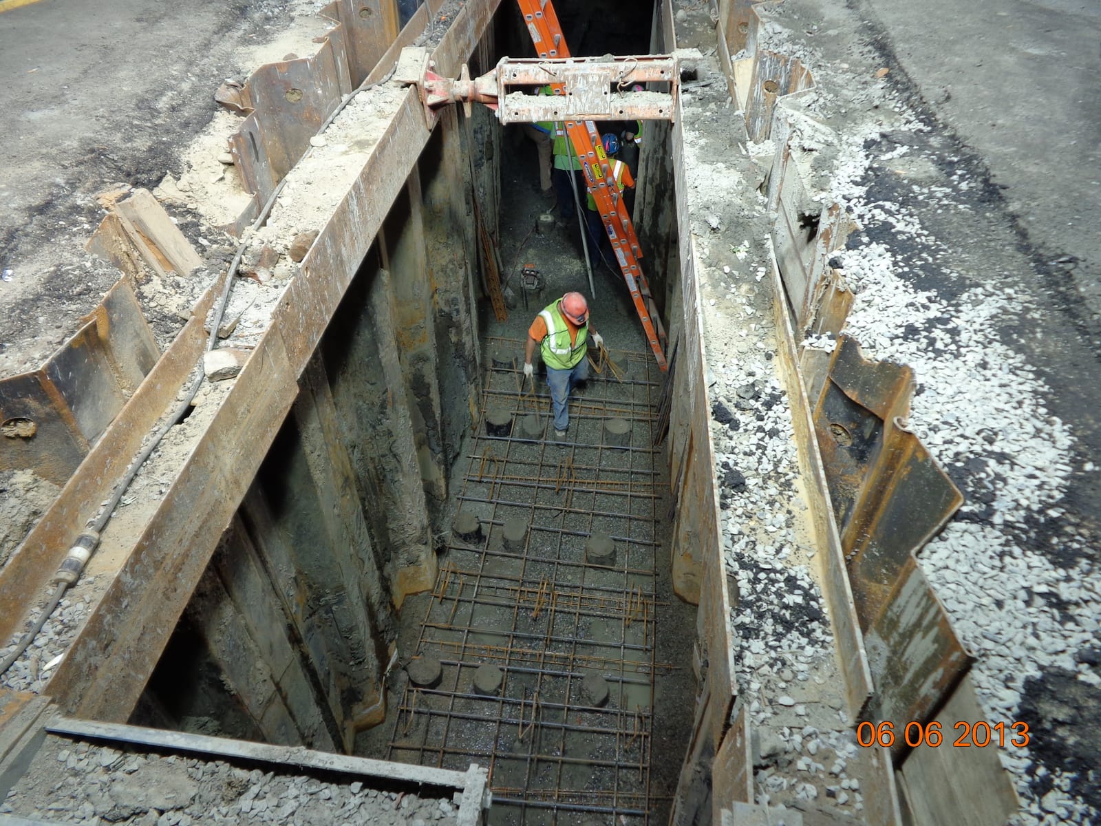 Worker in a shored open trench with rebar